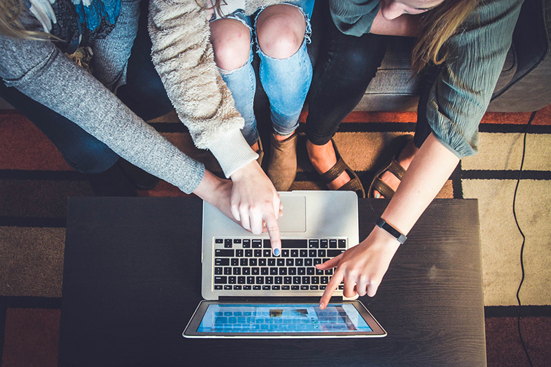 People talking around a laptop - VMAGROUP communications, marketing and digital recruitment