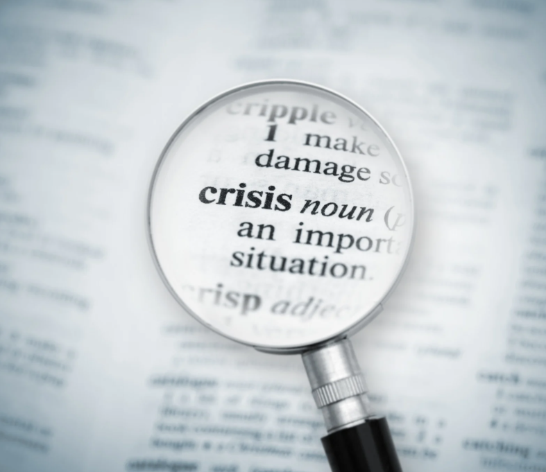 Magnifying glass over the word zooming in on the word 'crisis'